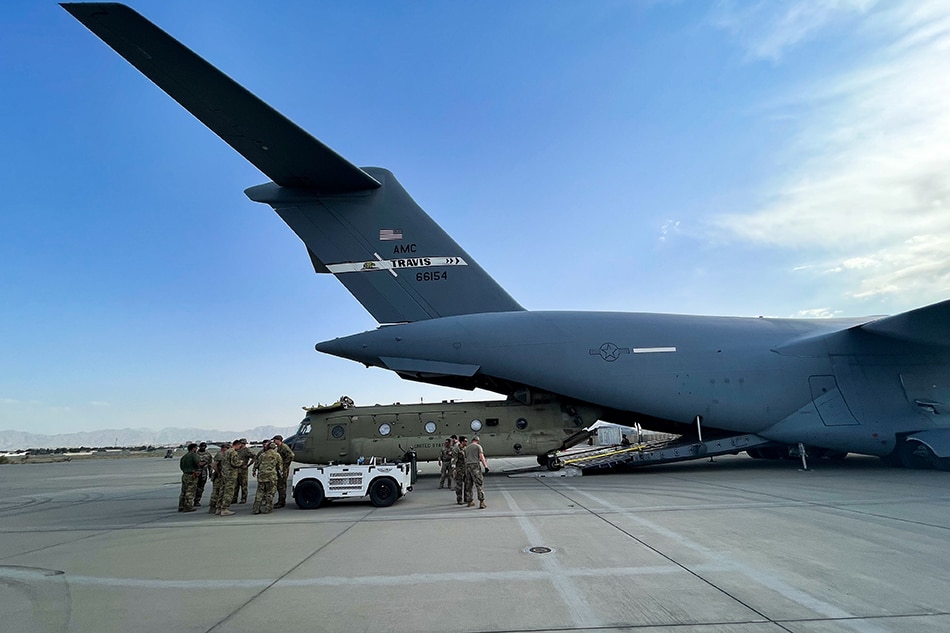 A CH-47 Chinook is loaded onto a U.S. Air Force C-17 Globemaster III at Hamid Karzai International Airport in Kabul, Afghanistan, August 28, 2021. The Chinook is one of the pieces of equipment returning to the U.S. as the military mission in Afghanistan comes to an end. Picture taken August 28, 2021. U.S. Central Command/Handout via Reuters