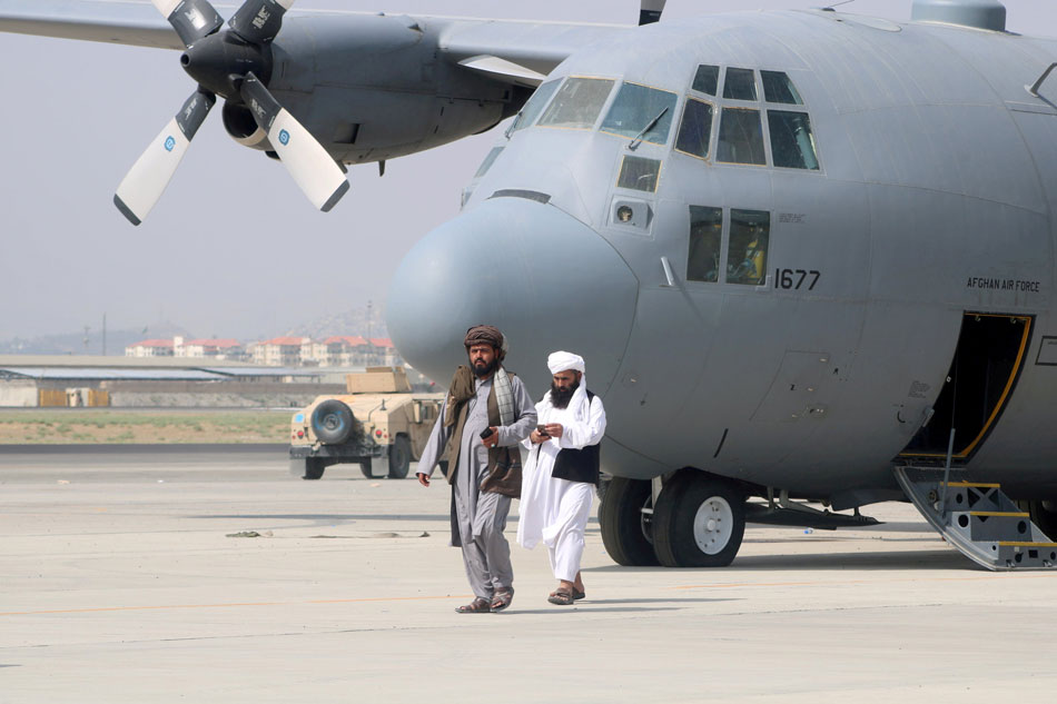 Taliban walk in front of a military airplane a day after US troops' withdrawal from Hamid Karzai International Airport in Kabul, Afghanistan on August 31, 2021. Stringer/Reuters
