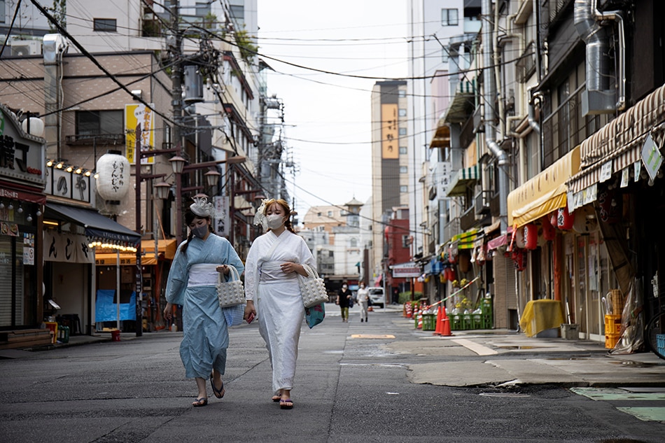 Women wear kimonos in the street at the Senso-ji temple area in Tokyo, Japan, Aug. 18, 2021. Molly Darlington, Reuters