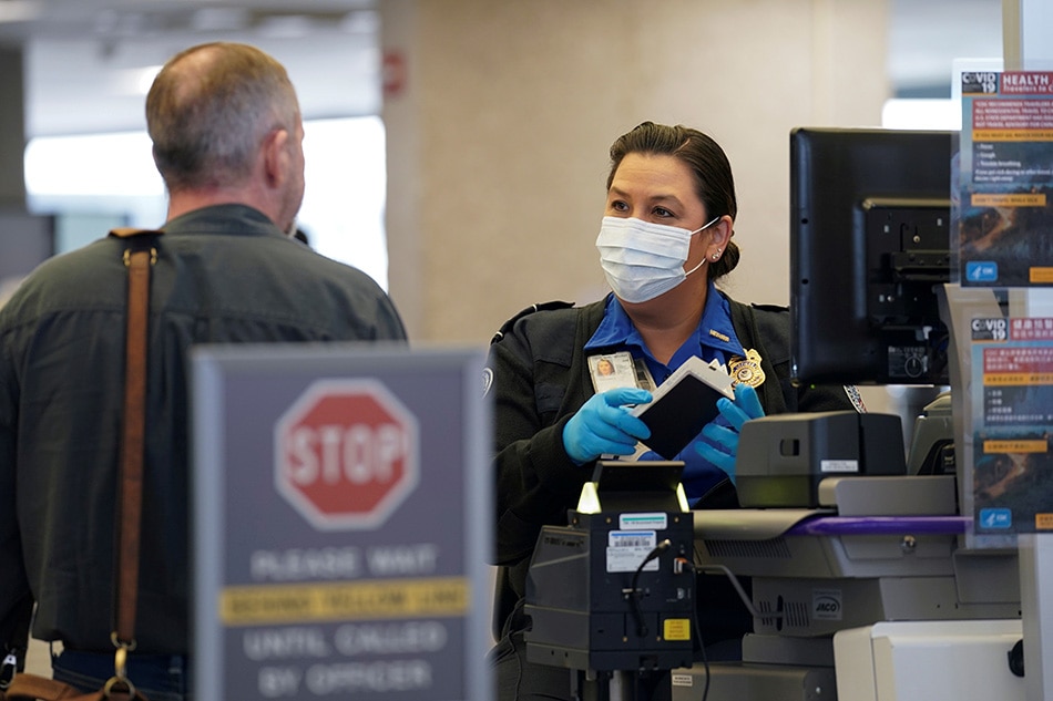 A TSA officer wearing a face mask clears a departing passenger at Dulles International Airport in Dulles, Virginia, US, March 12, 2020. Kevin Lamarque, Reuters/File