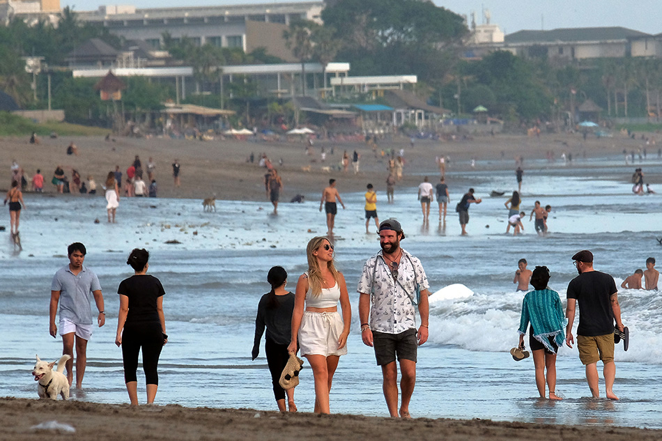 Tourists walk on a beach as the government extends restrictions to curb the spread of coronavirus disease in Badung, Bali, Indonesia September 9, 2021. Nyoman Hendra Wibowo, Antara Foto via Reuters
