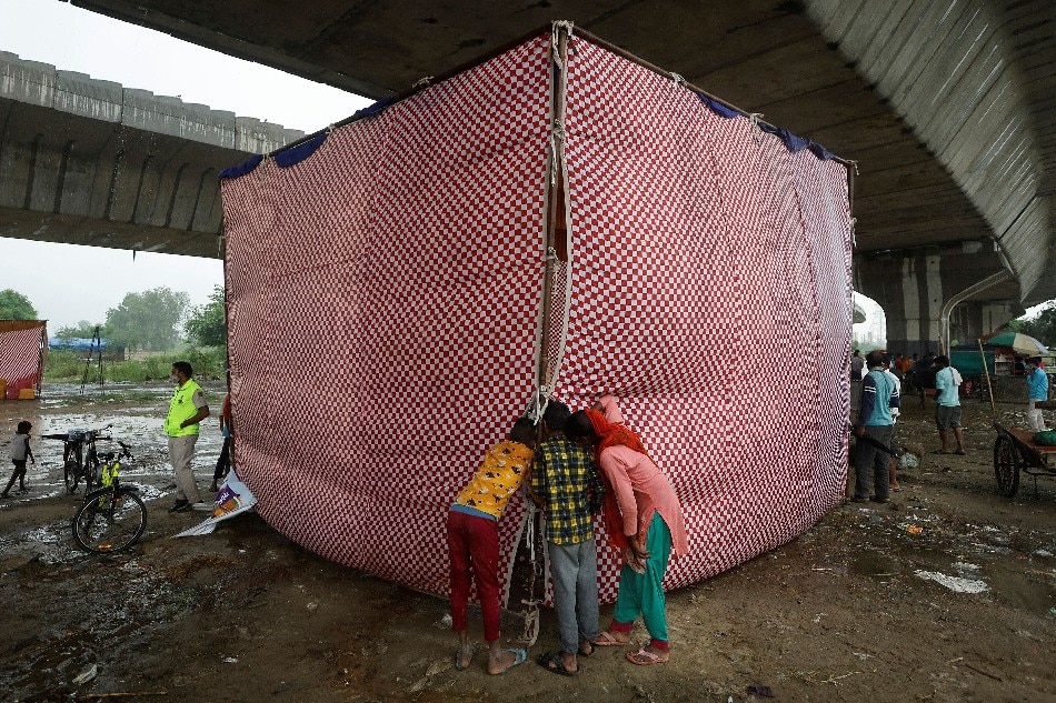 Children peep inside a tent where people receiving a dose of COVAXIN COVID-19 vaccine manufactured by Bharat Biotech, during a vaccination drive at an under-construction flyover in New Delhi, India, August 31, 2021. Adnan Abidi, Reuters