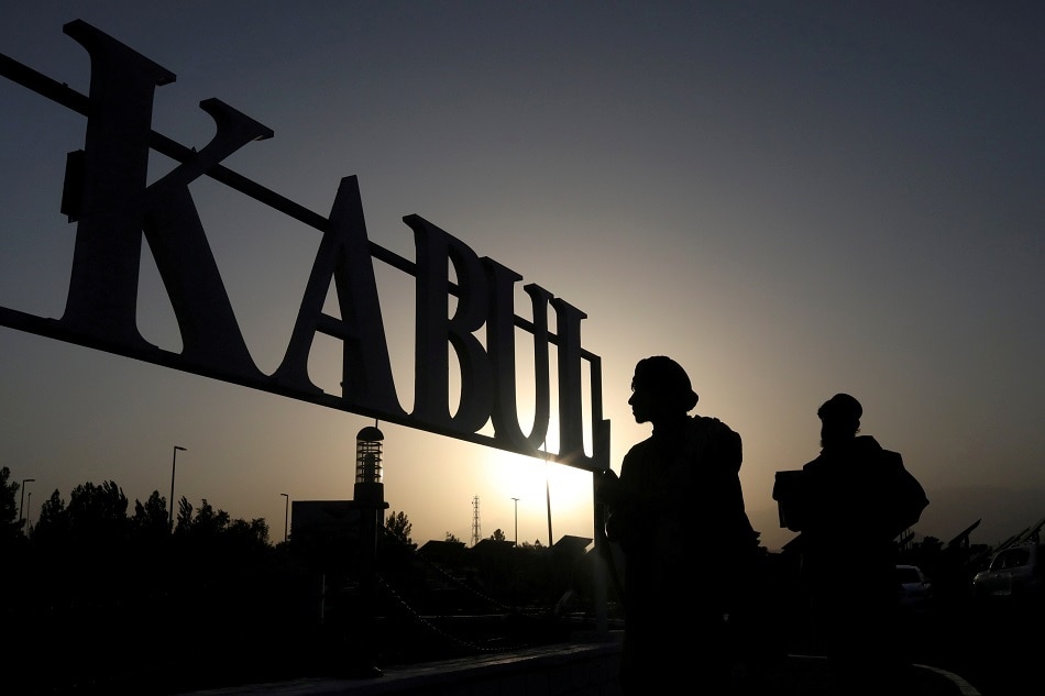 Taliban soldiers stand in front of a sign at the international airport in Kabul, Afghanistan, September 9, 2021. WANA (West Asia News Agency) via Reuters/file