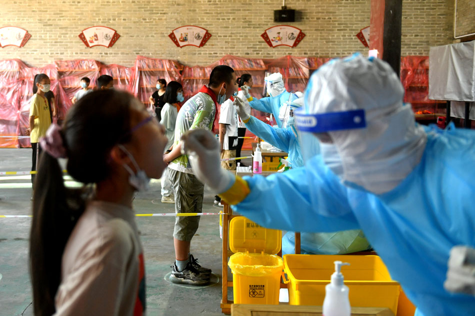 Medical workers wearing protective suits take swabs from primary school students at a nucleic acid testing site, following new cases of the coronavirus disease (COVID-19), in Fuzhou, Fujian province, China September 15, 2021. cnsphoto/via Reuters