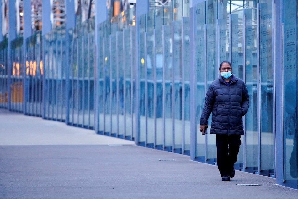A woman wearing a protective face mask walks along a deserted city bridge during morning commute hours on the first day of a lockdown in Victoria. Reuters file photo