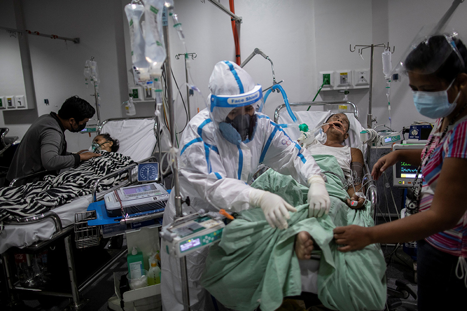 A health worker tends to a coronavirus disease (COVID-19) patient supported by a mechanical ventilator and undergoing dialysis at the COVID-19 emergency room of the government hospital National Kidney and Transplant Institute on April 26, 2021 in Quezon City, which has declared overcapacity following a surge of COVID-19 infections in Metro Manila. Eloisa Lopez, Reuters