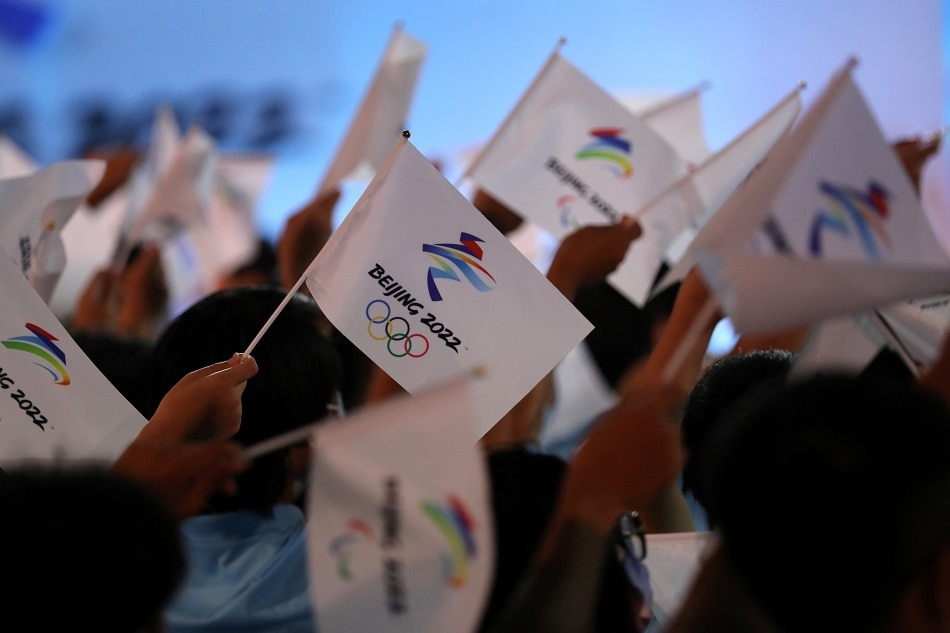 Attendees wave flags with the emblem of the Beijing 2022 Winter Olympic Games at a ceremony unveiling the slogan, in Beijing, September 17, 2021. Tingshu Wang, Reuters