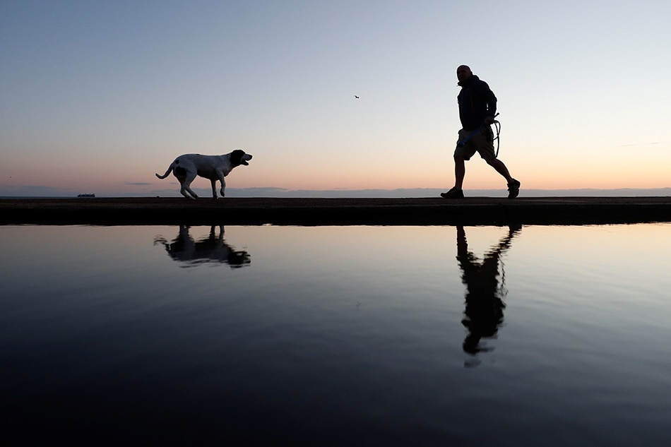 A man walks his dog on the beach in South Shields, Britain, October 10, 2021. REUTERS/Lee Smith