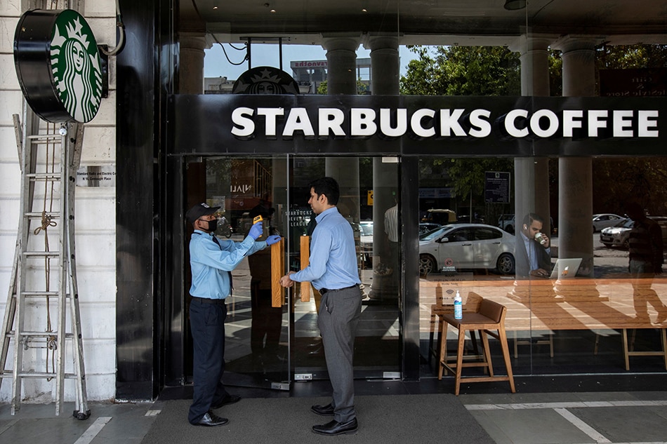 A private security guard checks the body temperature of a customer outside a Starbucks coffee shop, as a precaution against the spread of coronavirus, in New Delhi, India, March 17, 2020. Danish Siddiqui, Reuters/File Photo