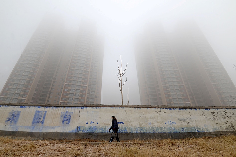 A woman wearing a mask walks past buildings on a polluted day in Handan, Hebei province, China January 12, 2019. Stringer, Reuters/File Photo