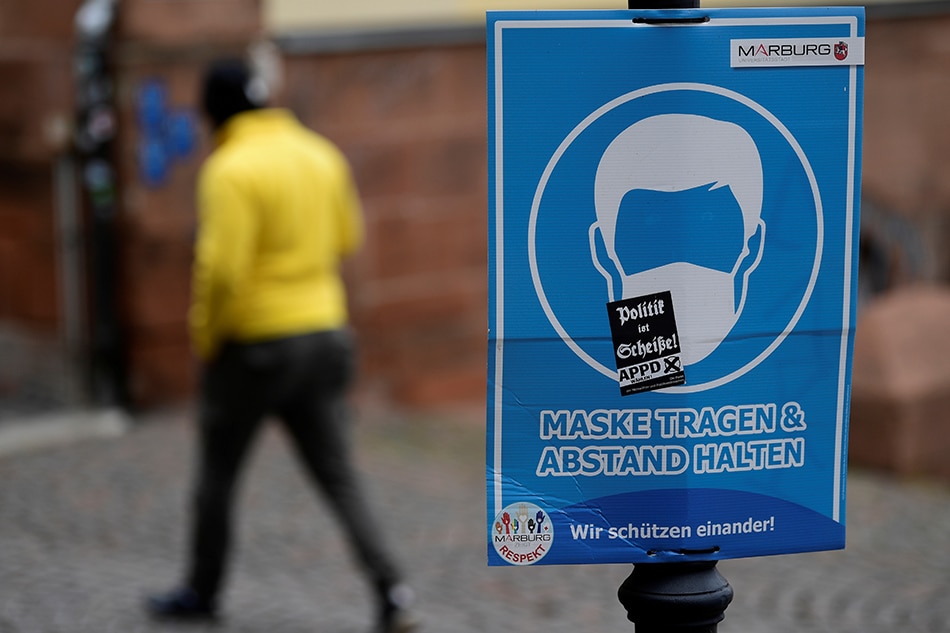 A person passes a sign, that indicates that masks are mandatory in Marburg, Germany, November 17, 2021. Fabian Bimmer, Reuters