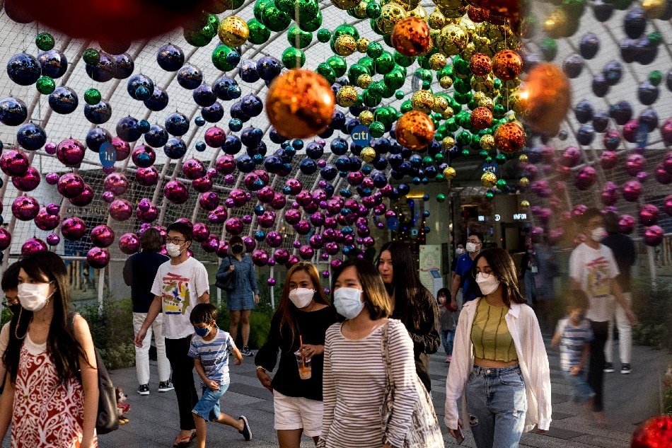 People wearing face masks walk below decorations outside a shopping mall in Bangkok on December 6, 2021 as Thailand recorded on Monday its first case of the Covid-19 coronavirus Omicron variant. Jack Taylor, Agence France-Presse