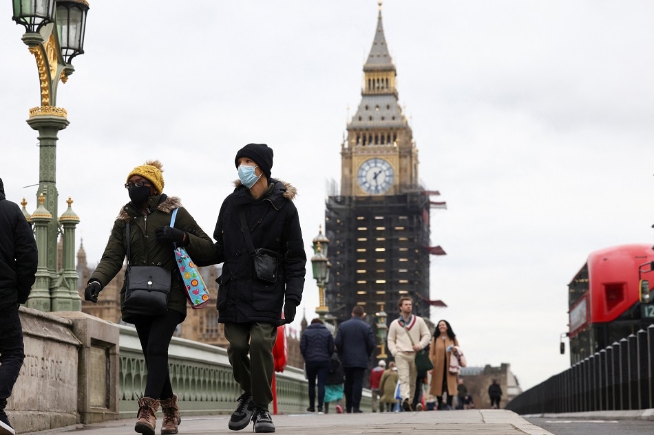 People wearing protective face masks walk over Westminster Bridge in front of the Elizabeth Tower, more commonly known as Big Ben, in London, Britain, on December 15, 2021. Henry Nicholls, Reuters