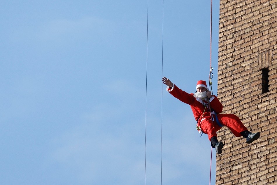 An Alpine Rescue Team member dressed as Santa Claus rappels down the Policlinico Umberto I Hospital to greet children hospitalized in the pediatric ward, in Rome, Italy, Dec. 23, 2021. Yara Nardi, Reuters