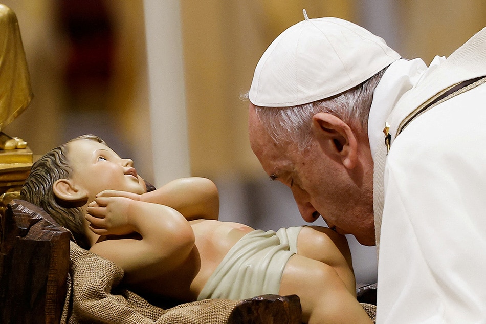 Pope Francis kisses a statue of baby Jesus as he celebrates Christmas Eve Holy Mass in St. Peter's Basilica at the Vatican, December 24, 2021. Guglielmo Mangiapane, Reuters
