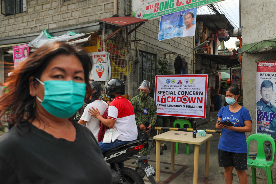 People walk past a sign informing the public regarding the imposition a granular lockdown at Block 4 alley along Scout Bayoran Street in Barangay South Triangle, Quezon City on Oct. 21, 2021. Jonathan Cellona, ABS-CBN NEWS