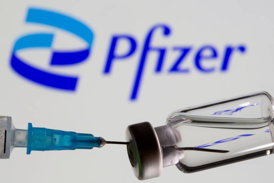Syringe and vial are seen in front of displayed new Pfizer logo in this illustration taken, June 24, 2021. Dado Ruvic, Reuters