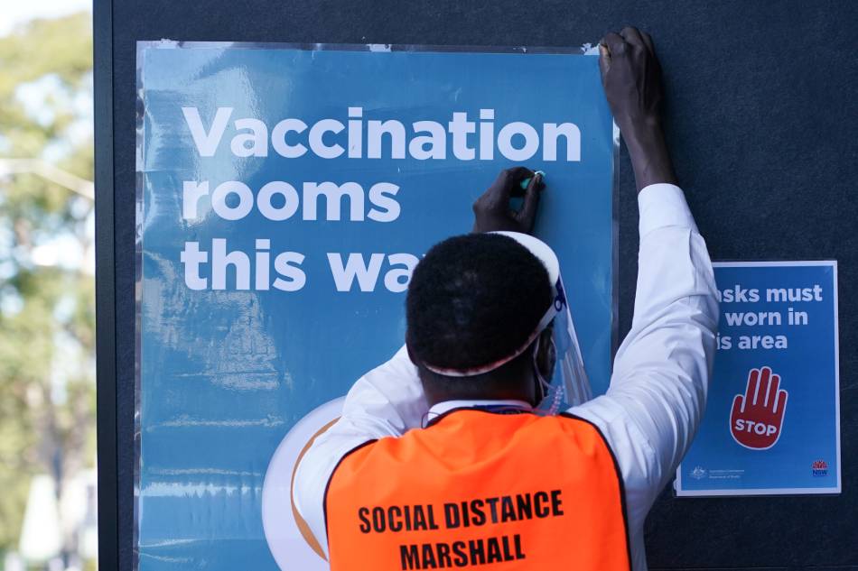 A staff member straightens a sign outside a coronavirus disease (COVID-19) vaccination clinic at the Bankstown Sports Club as the city experiences an extended lockdown, in Sydney, Australia, August 3, 2021. Loren Elliott, Reuters