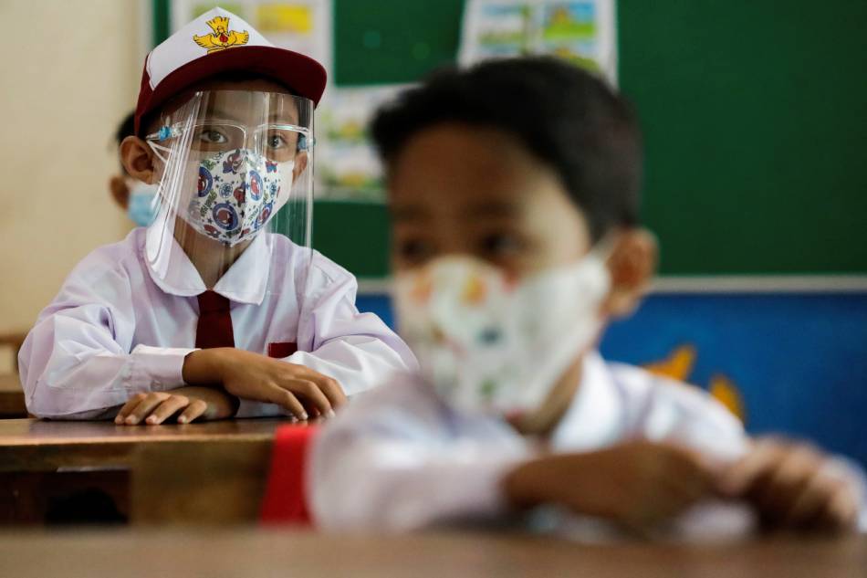 Elementary school students wearing face masks and face shields attend class, as schools reopen on a trial basis after the government extended restrictions to curb the spread of coronavirus disease (COVID-19) in Jakarta, Indonesia, August 30, 2021. Ajeng Dinar Ulfiana, Reuters/File