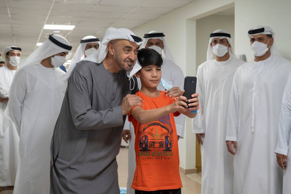 Abu Dhabi's Crown Prince Sheikh Mohammed bin Zayed al-Nahyan takes a photo with an Afghan boy, during his visit to evacuee families from Afghanistan at Emirates Humanitarian City in Abu Dhabi WAM/Handout via REUTERS