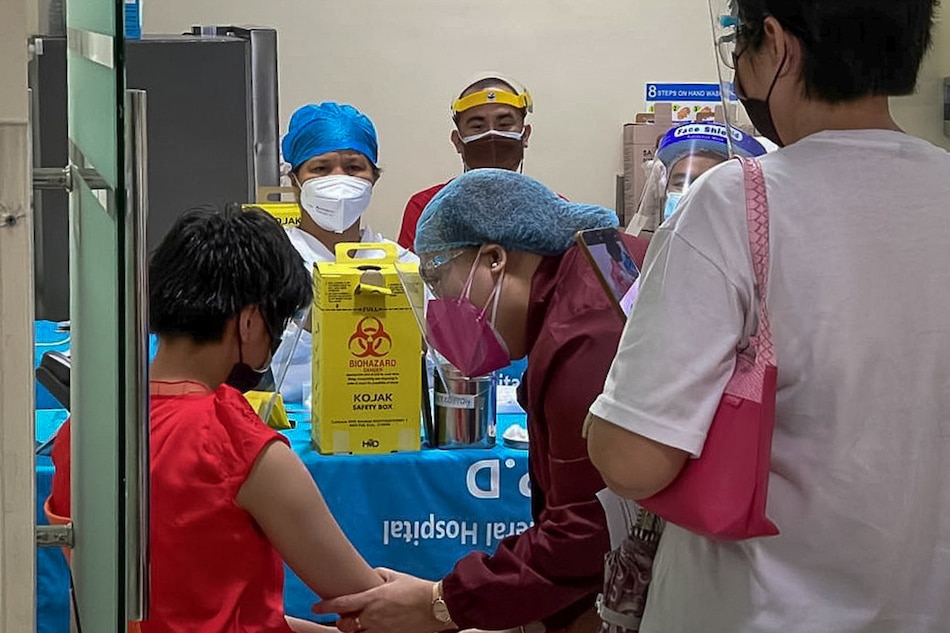 A health worker talks to a child before inoculating with Pfizer-BioNTech vaccine against the coronavirus disease (COVID-19), during the vaccine rollout for children with comorbidities, in Pasig City on October 15, 2021. The inoculation of minors started in Metro Manila for 12- to 17-year-olds with comorbidities to protect more people against more infectious coronavirus variants. Pasig City PIO handout/Reuters