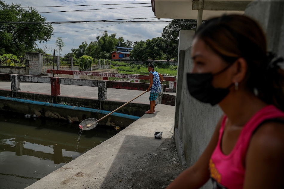 A resident walks along a stretch of a concrete dike as she looks for trash to fish out of from the nearby creek in Brgy. San Juan South in San Fernando, Pampanga on September 16, 2021, as part of an initiative for their barangay to keep the rivers and creeks clear of trash and debris. Jonathan Cellona, ABS-CBN News