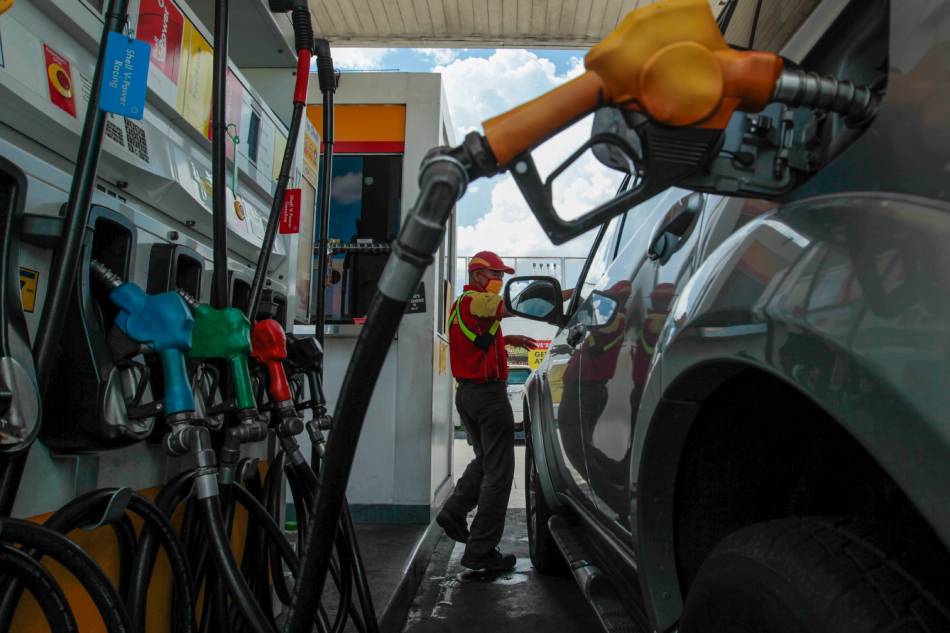 A gasoline station employee attends to motorists as they gas up at a refueling station in Quezon City on July 20, 2020. Jonathan Cellona, ABS-CBN News/File