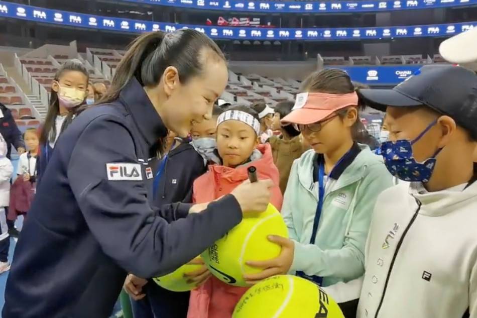 Chinese tennis player Peng Shuai signs large-sized tennis balls at the opening ceremony of Fila Kids Junior Tennis Challenger Final in Beijing, China November 21, 2021, in this screen grab obtained from a social media video. @QINGQINGPARIS via Reuters.