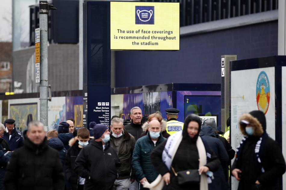 People walk under a sign encouraging them to wear protective face masks whilst in the stadium before the match in Tottenham Hotspur Stadium, London, Britain. December 5, 2021. Action Images via Reuters/Peter Cziborra, Reuters