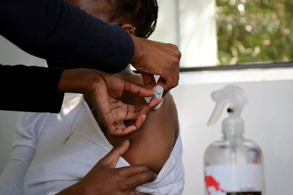 A health care worker administers the Johnson & Johnson COVID-19 vaccination to a woman in Houghton, Johannesburg, South Africa, Aug. 20, 2021. Sumaya Hisham, Reuters