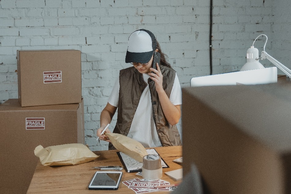 Photo source: Pexels [LINK OUT 'Pexels': https://www.pexels.com/photo/woman-having-a-phonecall-while-looking-at-a-parcel-6169053/