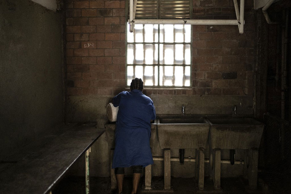 A woman can be seen washing clothes in a bathroom tap at Helen Joseph Women's Hostel in Alexandra Township on February 17, 2022. The rule has not changed since apartheid: the place is forbidden to men. In this ramshackle abode in Alexandra, one of South Africa's most destitute townships, thousands of black women live huddled in filth and fear of crime. Guillem Sartorio, AFP