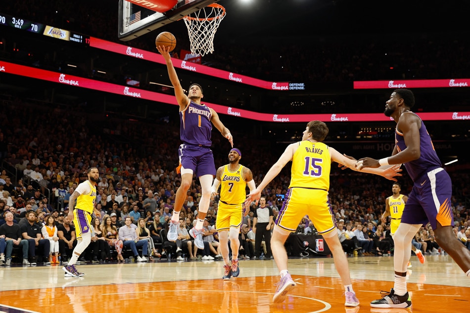 Devin Booker #1 of the Phoenix Suns lays up a shot against Austin Reaves #15 of the Los Angeles Lakers during the second half of the NBA game at Footprint Center on April 05, 2022 in Phoenix, Arizona. Christian Petersen/Getty Images/AFP
