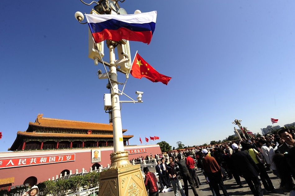 People pass by Chinese and Russian flags flying at Tiananmen Gate in honor of the visit of Russian Prime Minister Vladimir Putin in Beijing on October 13, 2009. Peter Parks, AFP/file
