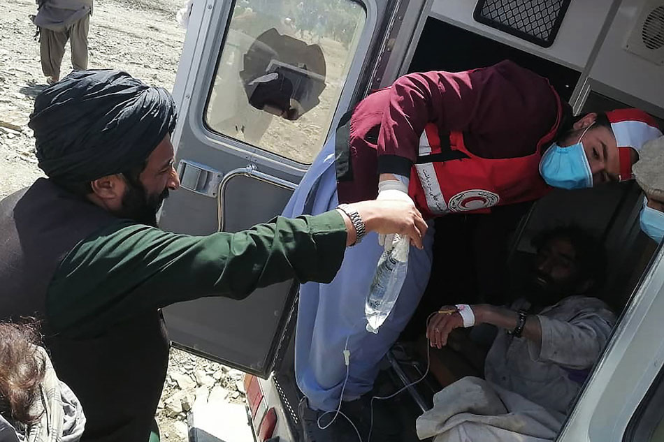  This photograph taken on June 22, 2022 and received as a courtesy of the Afghan government-run Bakhtar News Agency shows a member of the Afghan Red Crescent Society giving medical treatment to a victim following an earthquake in Afghanistan's Gayan district, Paktika province overnight. Bakhtar News Agency/AFP
