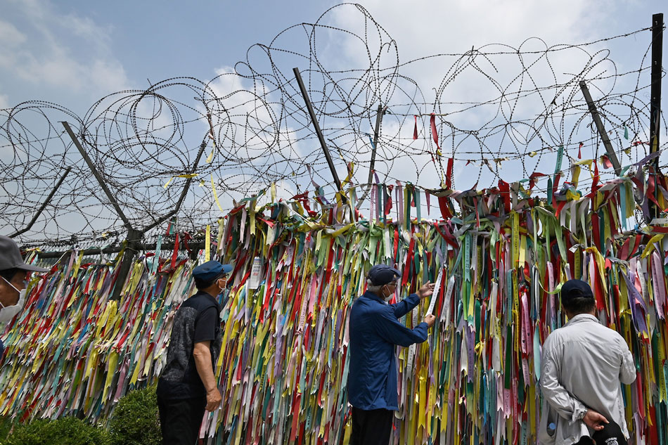 Visitors look at ribbons wishing for peace and reunification of the Korean Peninsula on a military fence at Imjingak peace park, near the Demilitarized Zone (DMZ) dividing the two Koreas in the border city of Paju on June 16, 2020. Jung Yeon-je, AFP/File 
