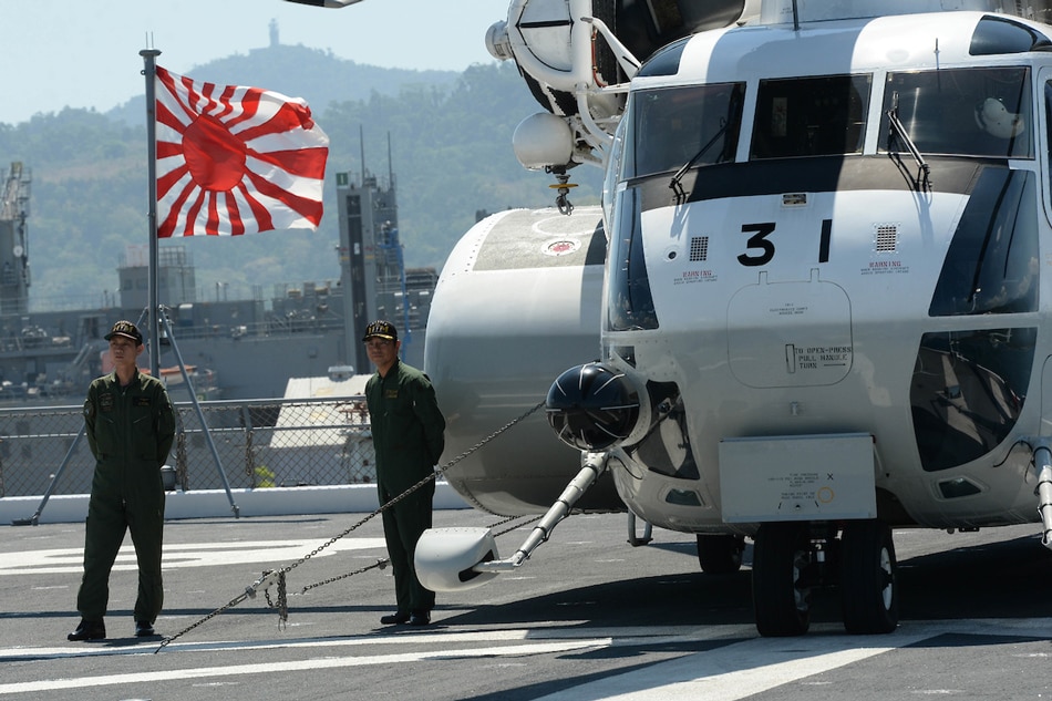 Crew of Japan's helicopter carrier Ise stand on the deck next to a flag shortly after arriving at the former US naval base, Subic port, north of Manila on April 26, 2016. Ted Aljibe, AFP Photo/File 