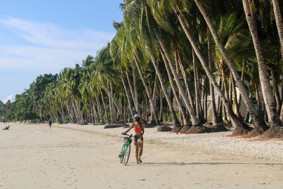   Un résident portant un masque facial se promène le long d'une plage de Borocay jeudi, premier jour de l'ouverture de l'île aux touristes pendant la pandémie de COVID-19.  AFP/dossier