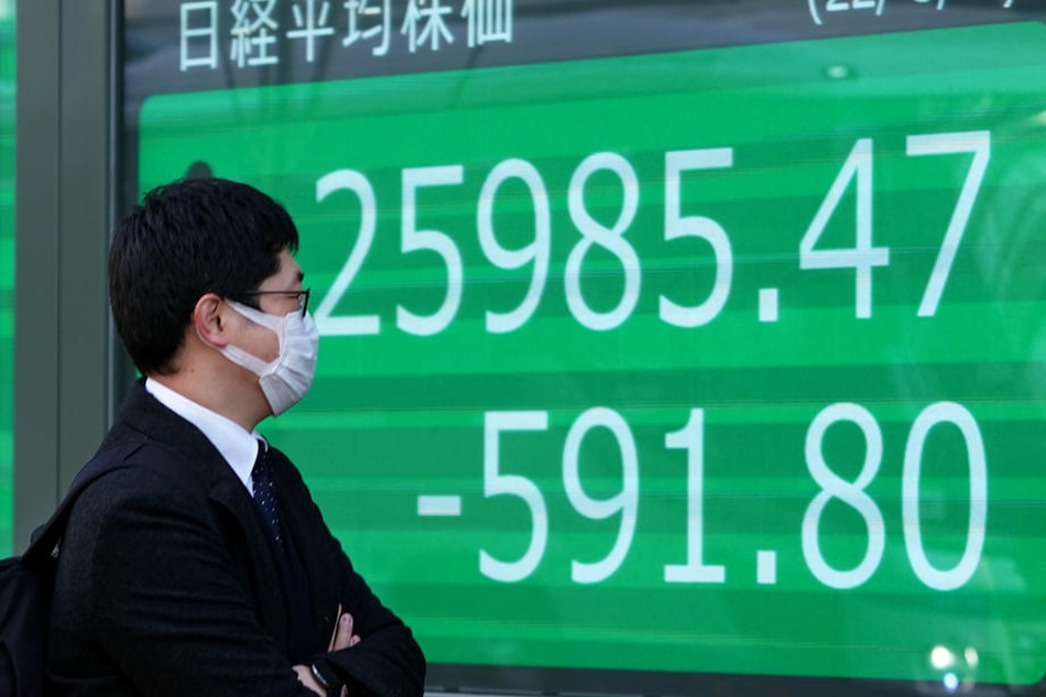 A pedestrian walks past a display showing closing information of Tokyo's Nikkei Stock Average in Tokyo, Japan, March 4, 2022. Kimimasa Mayama, EPA-EFE