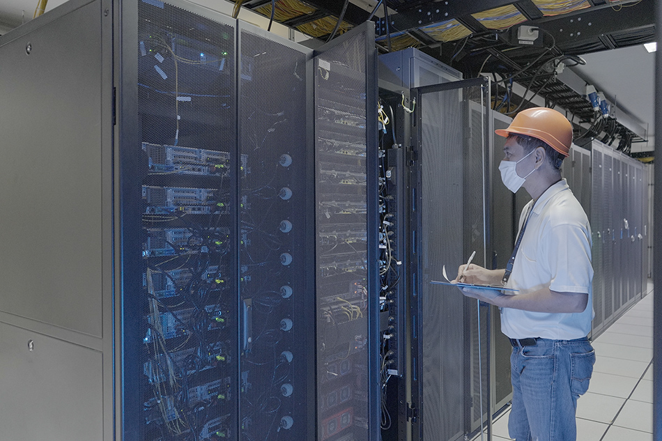 An engineer inspects a rack at the Converge Pampanga data center, now running on 100 percent renewable energy. Handout