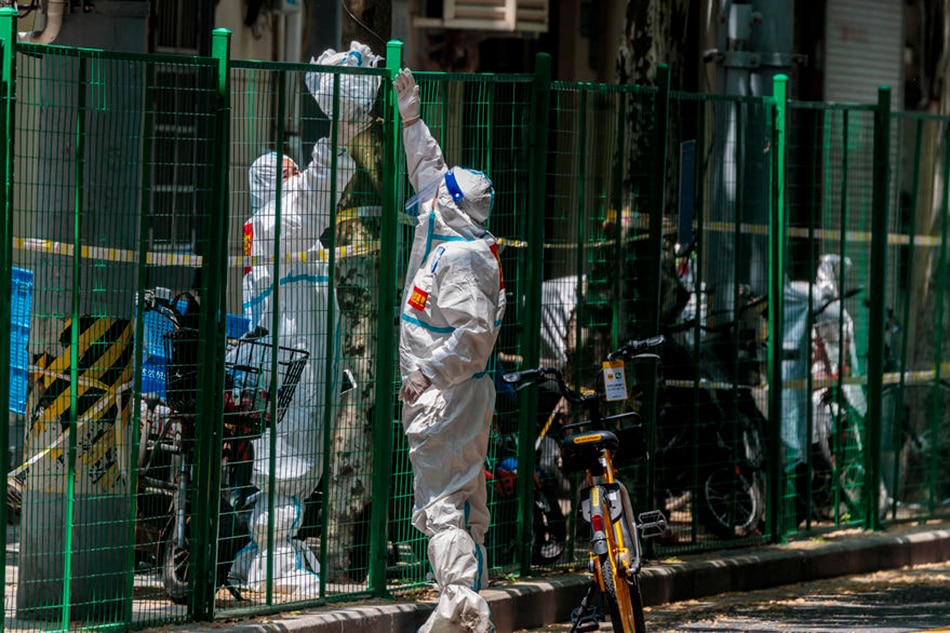 People exchange protective gear over the fence on the street, amid COVID-19 lockdown of the city in Shanghai, China, 02 May 2022. Alex Plavevski, EPA-EFE 