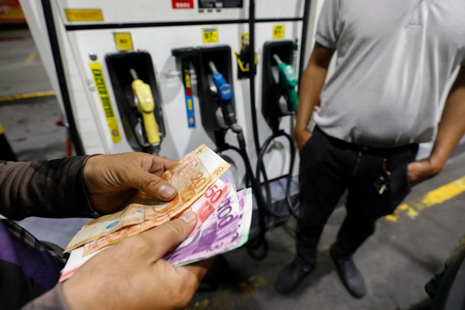 A customer (L) counts Philippine peso bills to pay at a fuel station in Quezon City, Metro Manila, Philippines, 08 March 2022. Rolex Dela Pena, EPA-EFE