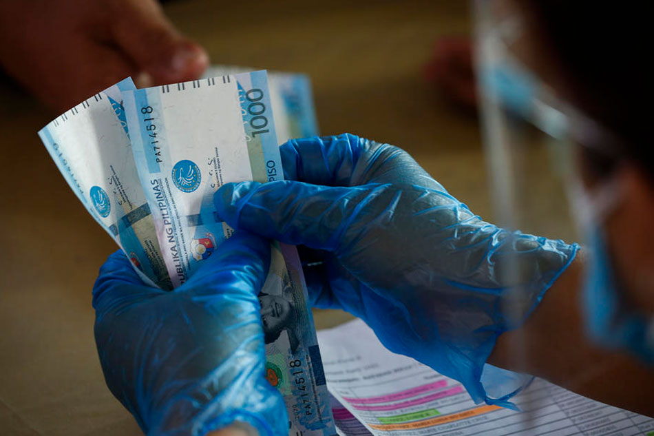 A local government worker wears gloves while counting Philippine peso bills during a financial aid distribution program for families affected by the COVID-19 lockdown measures in Quezon City, Metro Manila, Philippines, 09 April 2021. Rolex Dela Pena, EPA-EFE/File