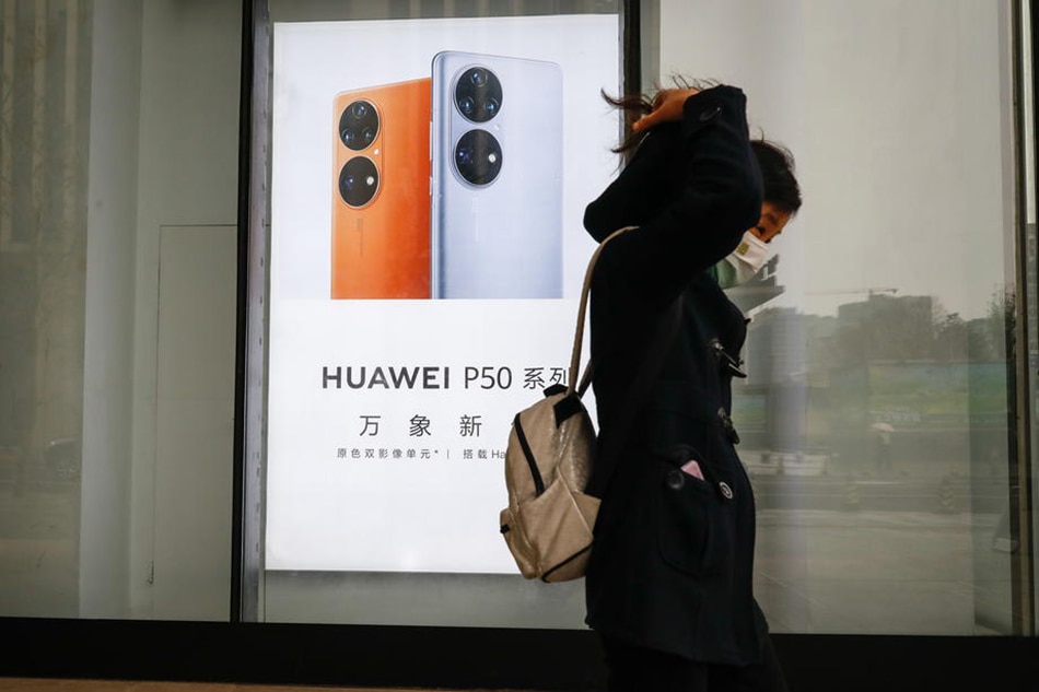 A woman walks past a Huawei advertisement in Beijing, China, March 29, 2022. Mark Cristino, EPA-EFE/File