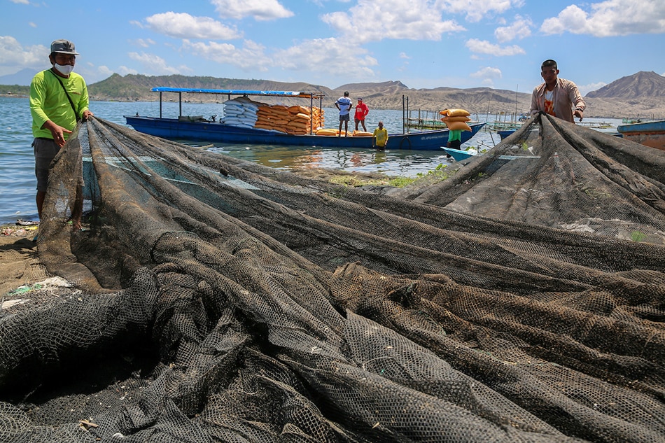 Fishpen workers load up on fish feeds on a boat as Alert Level 3 remain imposed over Taal volcano lake in Batangas on March 30, 2022. Jonathan Cellona, ABS-CBN News