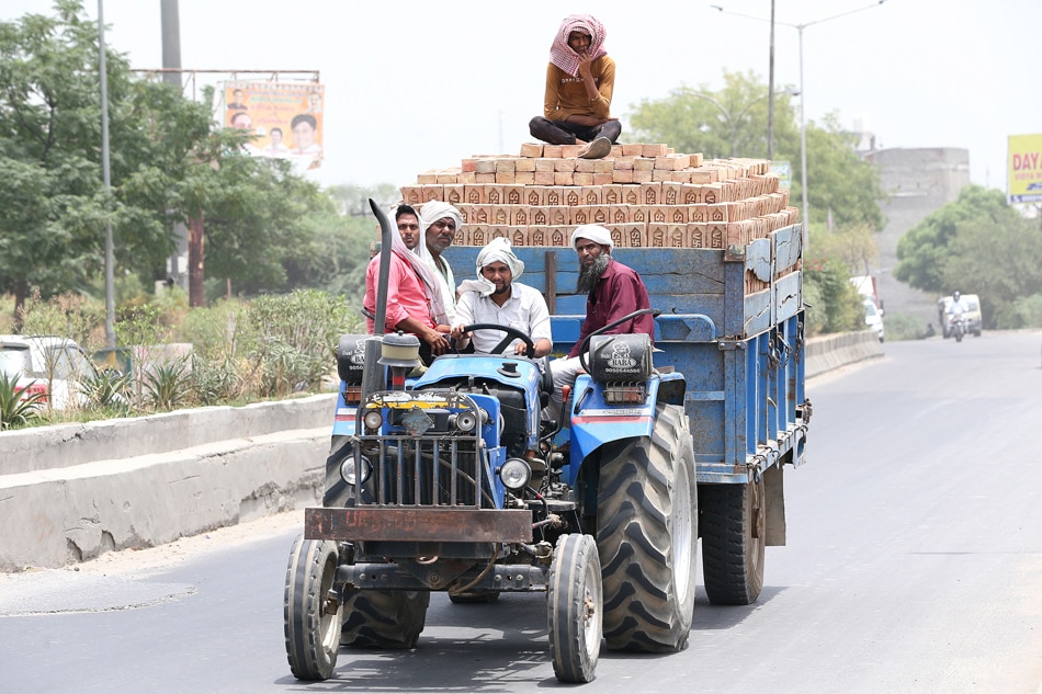 Indian people sit on a tractor during a hot afternoon on the outskirts of New Delhi, India, 19 May 2022. Harish Tyagi, EPA-EFE