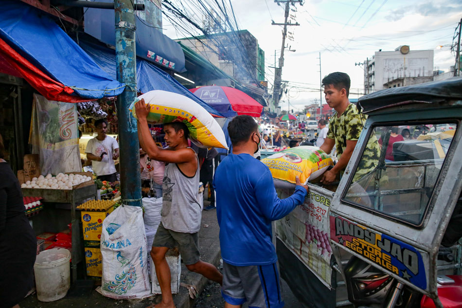 Workers unload sacks of rice at a public market in Makati City on May 31, 2022. George Calvelo, ABS-CBN News