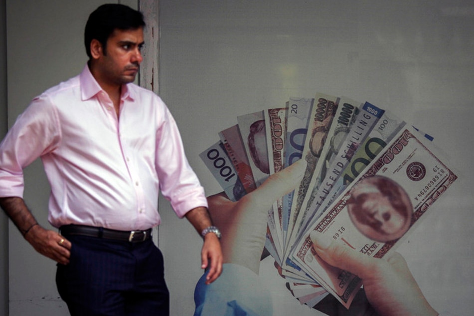 An Indian man walks past an advertisement of a foreign currency exchange, in Mumbai, India, 21 August 2013. EPA/DIVYAKANT SOLANKI/FILE