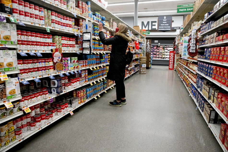 A customer looks at canned goods at a grocery store in Arlington, Virginia, USA, 25 Jan. 2022. Michael Reynolds, EPA-EFE/File