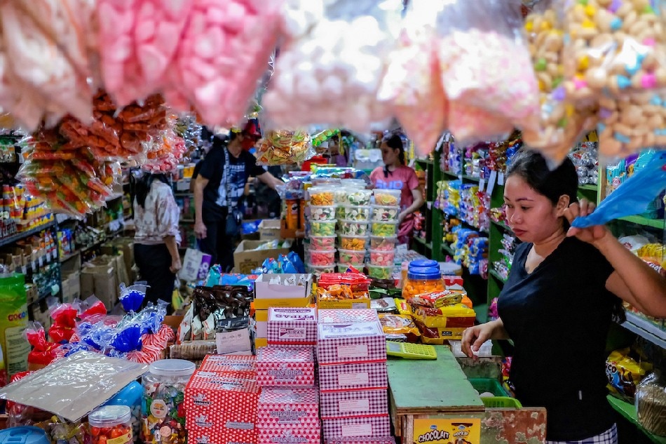 Store clerks attend to customers inside a mini grocery selling snacks and various sweets in Manila on August 17, 2022. George Calvelo, ABS-CBN News